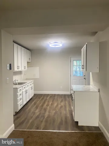 a kitchen with granite countertop a sink cabinets and wooden floor