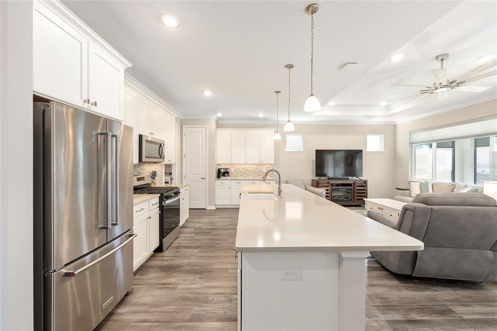 10390 Southwest 99th Street Ocala, FL 34481 - Photo 20 of 48 a large kitchen with stainless steel appliances kitchen island granite countertop a refrigerator a stove a sink a dining table and chairs with wooden floor