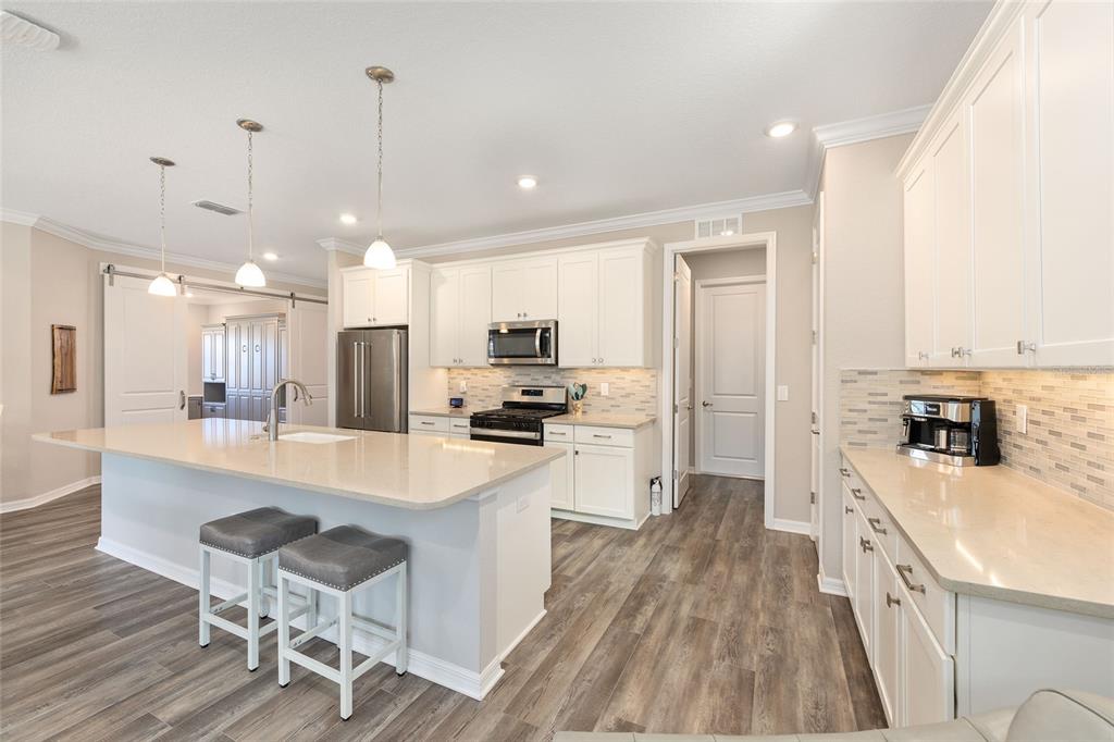 10390 Southwest 99th Street Ocala, FL 34481 - Photo 23 of 48 a large kitchen with kitchen island a large counter top space a sink stainless steel appliances and cabinets