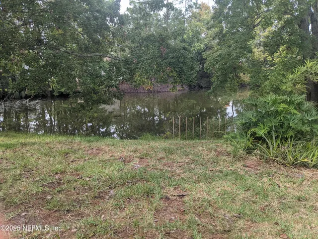 an empty room with wooden floor and kitchen view