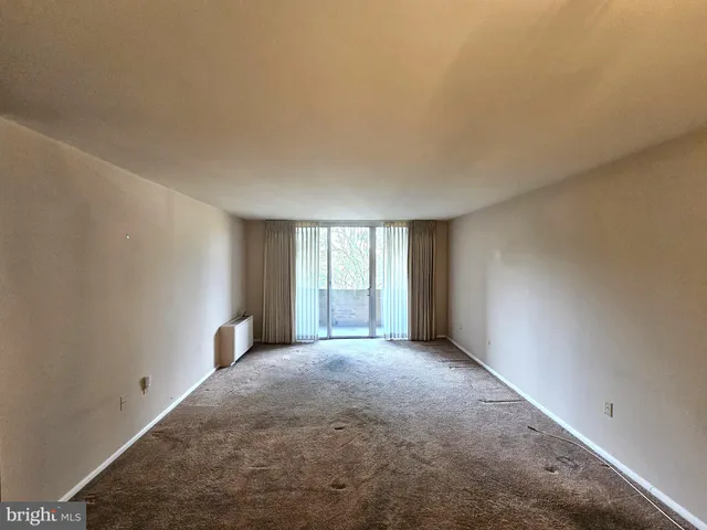 an empty room with kitchen chandelier and refrigerator