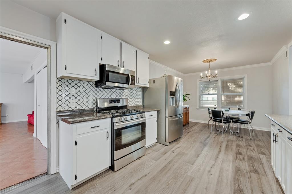 11310 Sinclair Avenue Dallas, TX 75218 - Photo 12 of 26 a kitchen with stainless steel appliances a stove top oven a refrigerator a dining table and chairs with wooden floor