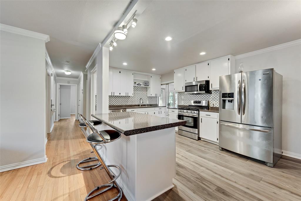 11310 Sinclair Avenue Dallas, TX 75218 - Photo 9 of 26 a kitchen with kitchen island white cabinets and stainless steel appliances