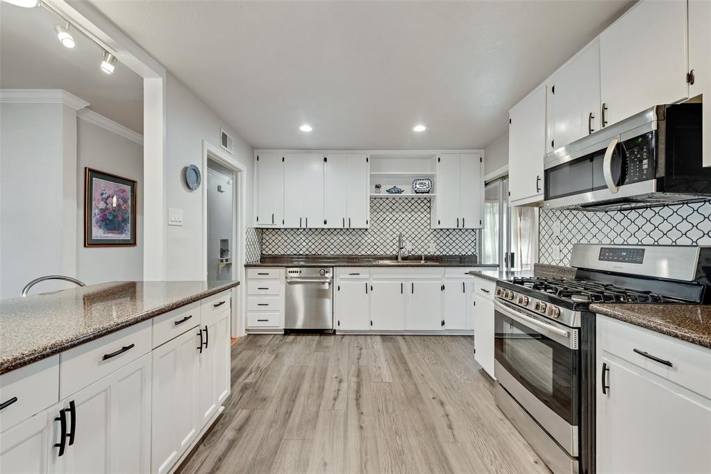 11310 Sinclair Avenue Dallas, TX 75218 - Photo 10 of 26 a large white kitchen with granite countertop a stove top oven a sink a counter space and cabinets