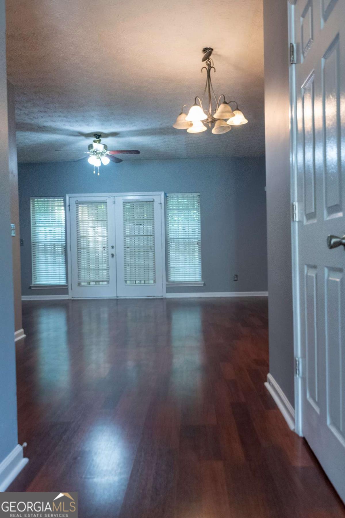 4123 Stone Trace Drive East Point, GA 30344 - Photo 21 of 24 an empty room with wooden floor chandelier and windows