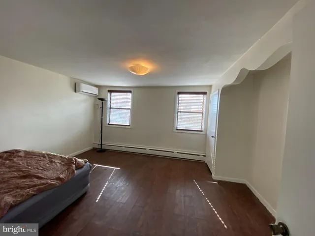 a view of a bedroom with wooden floor and window