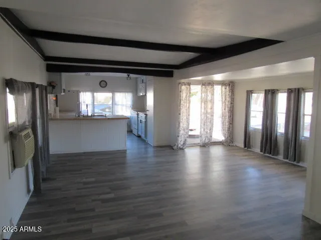 a view of an empty room with wooden floor and a kitchen