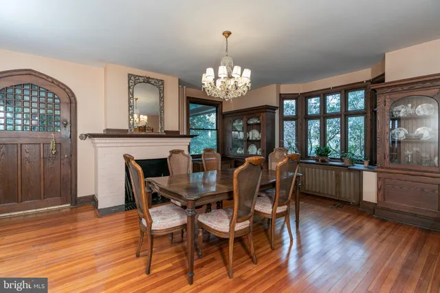 a dining room with wooden floor a chandelier a wooden table and chairs