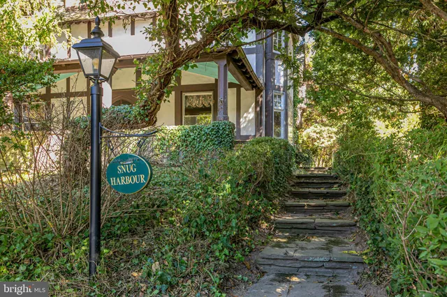 a front view of a house with a garden and trees