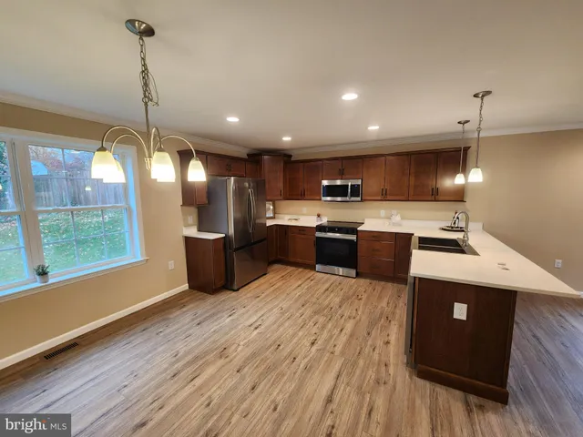 a kitchen with stainless steel appliances a refrigerator sink and wooden floor