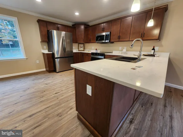 a large kitchen with stainless steel appliances wooden floors wooden cabinets a sink and a island
