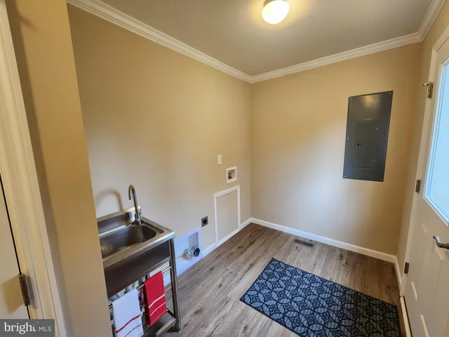 a view of a hallway with wooden floor and a bathroom