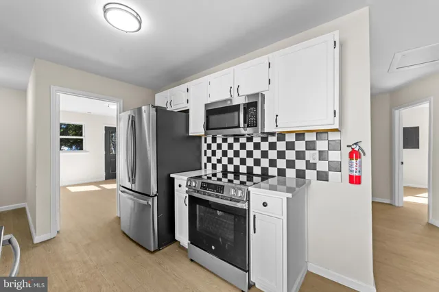 a kitchen with granite countertop white cabinets and stainless steel appliances