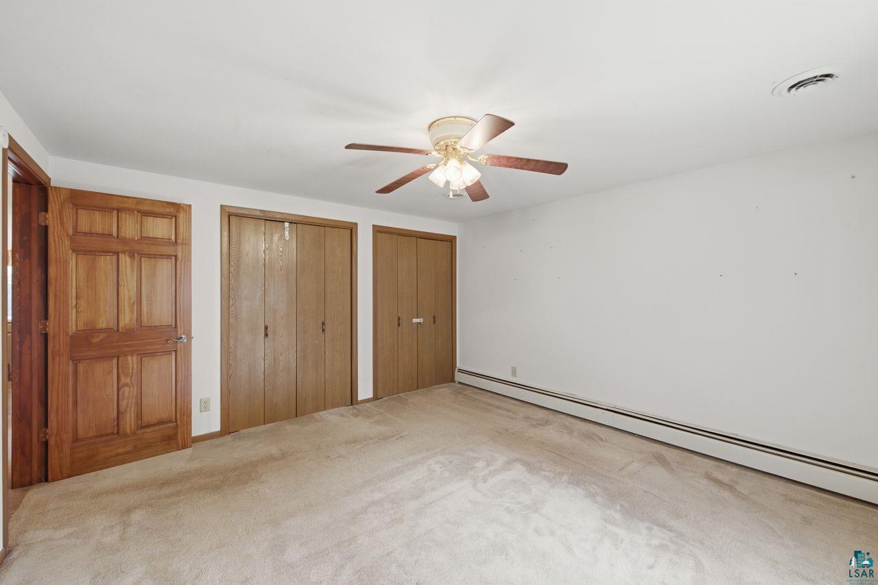 61018 Dahlstrom Road Ashland, WI 54806 - Photo 5 of 28 Carpeted room featuring a ceiling fan with integrated lighting, a paneled wood door, and two bifold closet doors