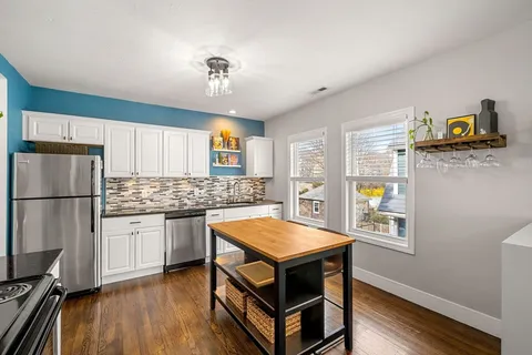 a kitchen with stainless steel appliances granite countertop a sink dishwasher stove and refrigerator with wooden floor