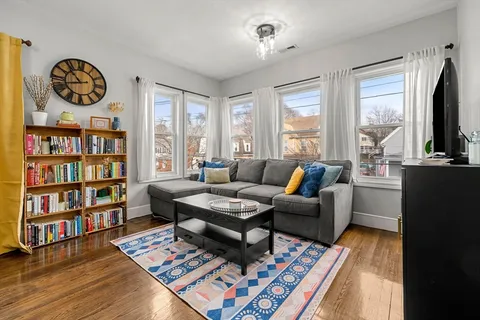 a living room with furniture a bookshelf and a window