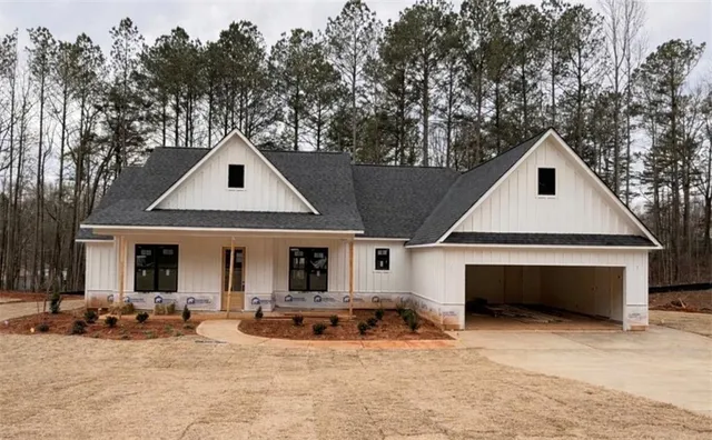 a view of a white house with large trees and couches chairs