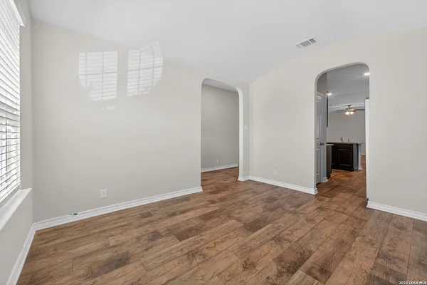 an empty room with wooden floor and windows