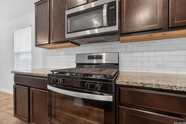a kitchen with granite countertop cabinets stove top oven and microwave