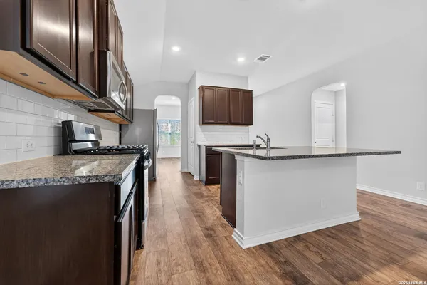 a kitchen with stainless steel appliances granite countertop a stove a sink and a refrigerator