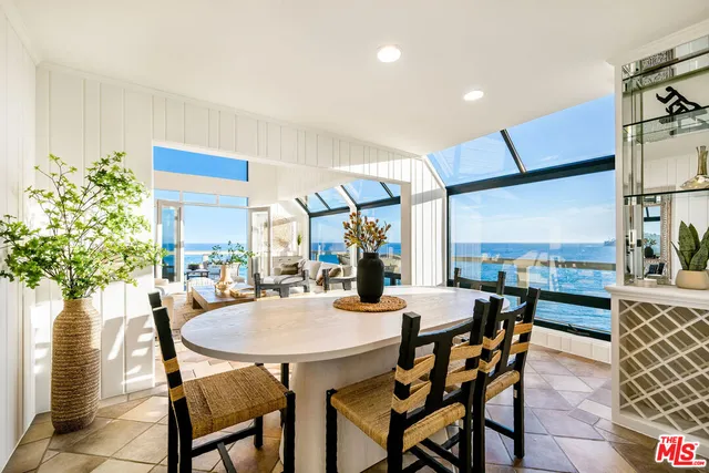 a view of a dining room and livingroom with furniture wooden floor a rug a potted plant and a chandelier
