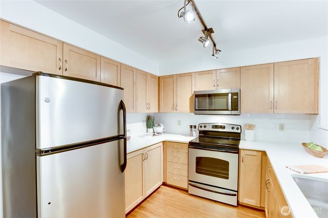 a kitchen with stainless steel appliances a refrigerator sink and white cabinets