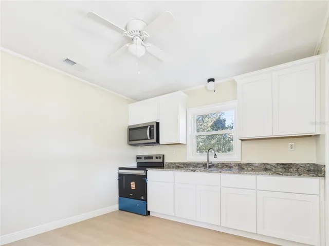 a kitchen with granite countertop a sink cabinets and stainless steel appliances