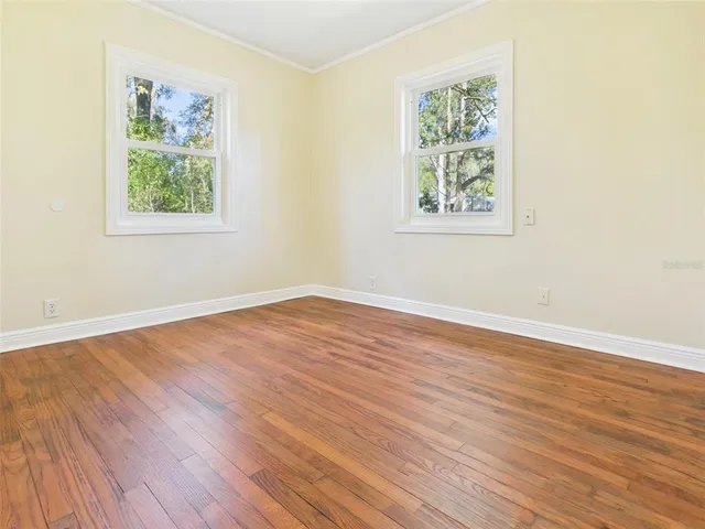 an empty room with wooden floor and window