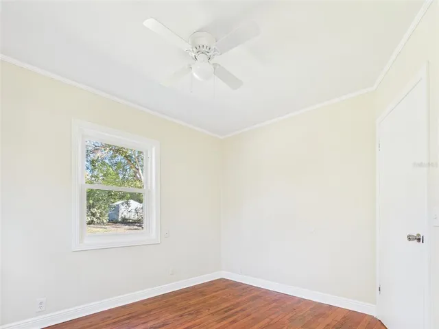 an empty room with wooden floor fan and windows