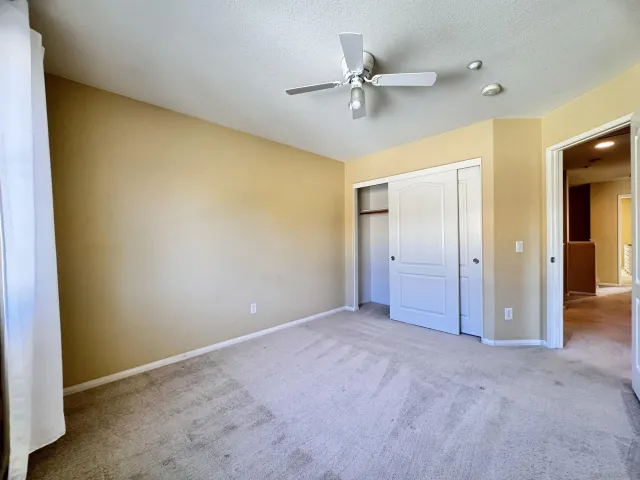 an empty room with a ceiling fan and window