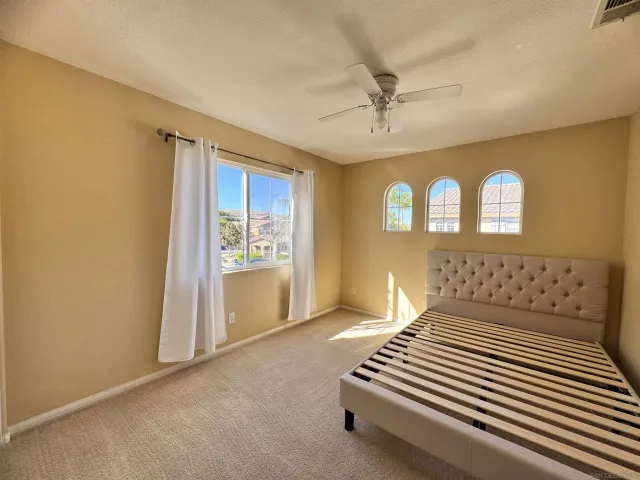 an empty room with windows and chandelier fan