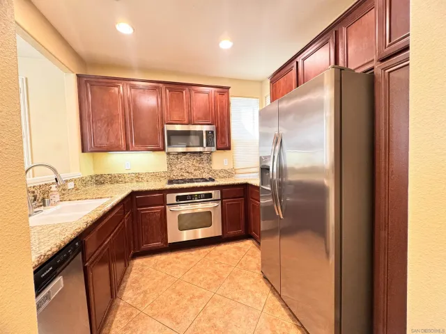a kitchen with stainless steel appliances granite countertop a refrigerator and a sink