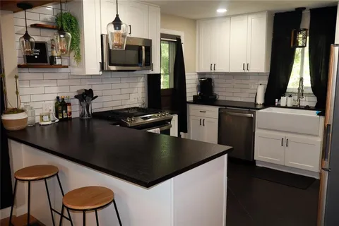 a kitchen with stainless steel appliances granite countertop a stove top oven a sink a dining table and chairs