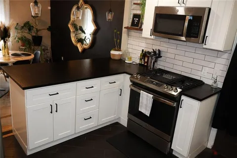 a kitchen with stainless steel appliances a stove a microwave a sink and cabinets