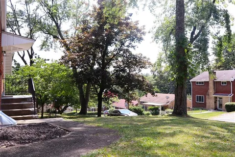 a front view of a house with a garden and tree