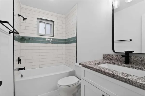 a bathroom with a granite countertop sink a toilet and bathtub