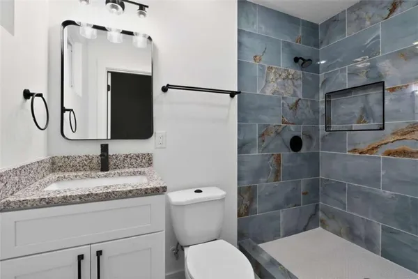 a bathroom with a granite countertop sink toilet and shower