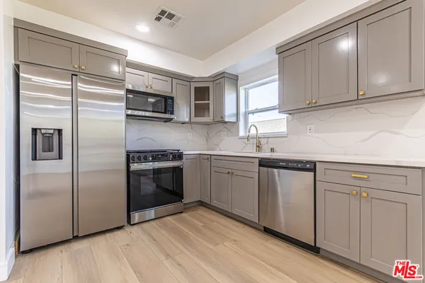 a kitchen with stainless steel appliances granite countertop a refrigerator and a sink