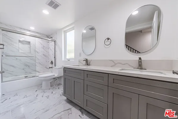 a spacious bathroom with a double vanity sink double mirror bathtub and toilet