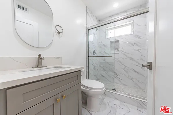 a bathroom with a granite countertop sink a mirror and a shower
