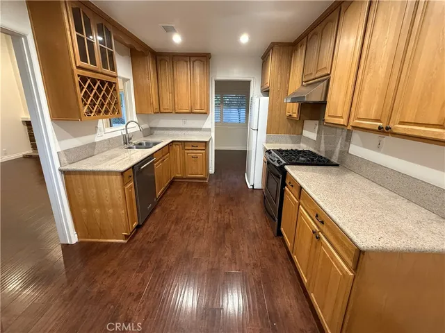a kitchen with stainless steel appliances granite countertop a sink a stove and a wooden floors