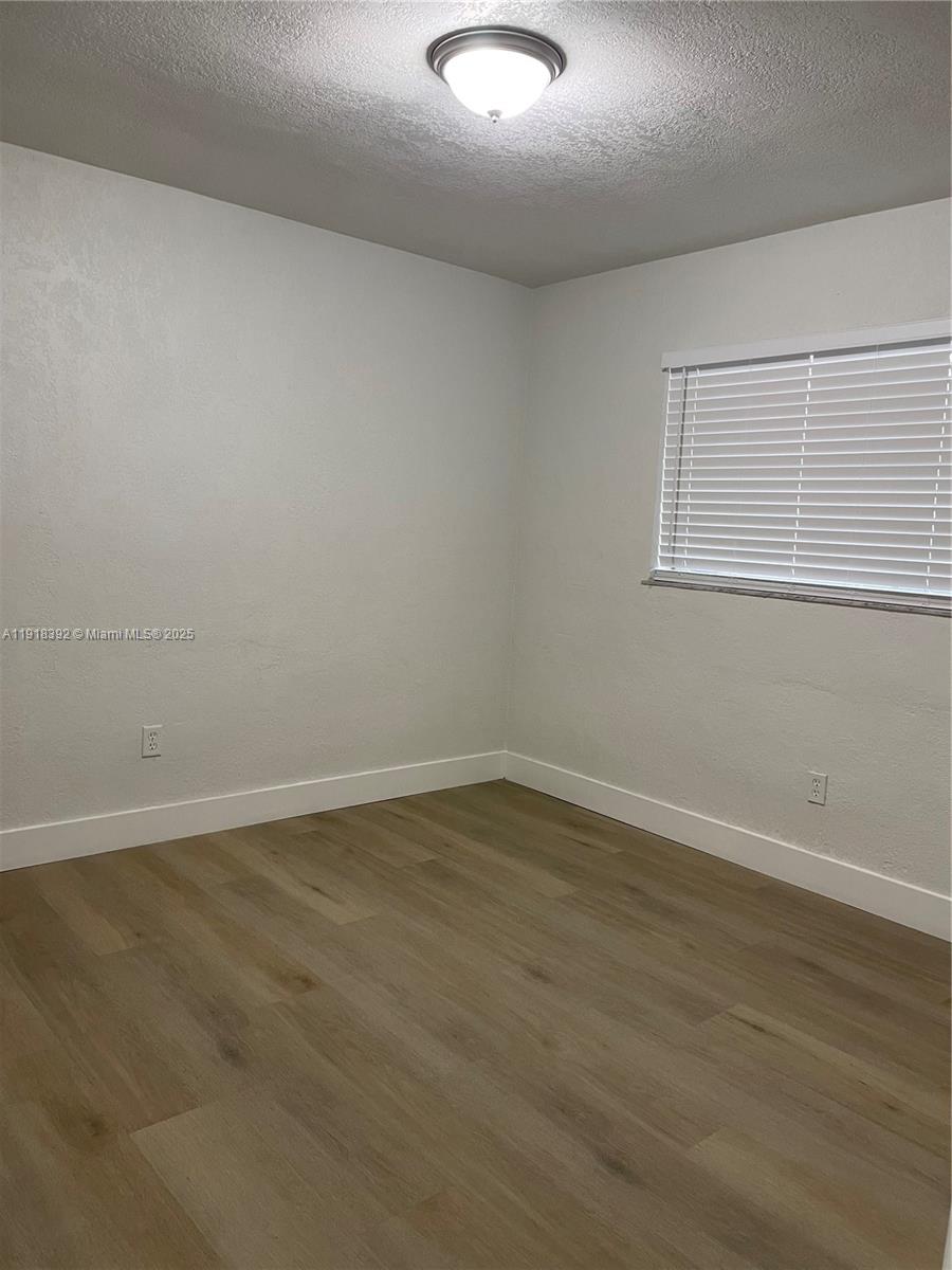 5261 Northwest 1st Street, Unit FRONT Miami, FL 33126 - Photo 13 of 14 an empty room with wooden floor and windows