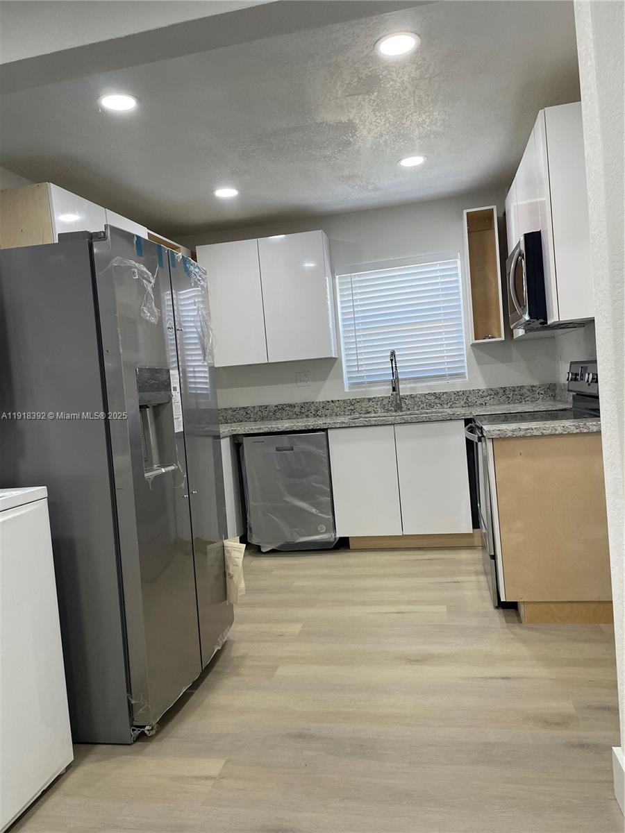 5261 Northwest 1st Street, Unit FRONT Miami, FL 33126 - Photo 4 of 14 a kitchen with granite countertop a refrigerator and a sink