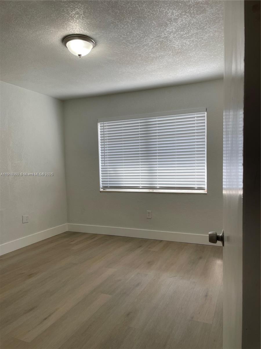 5261 Northwest 1st Street, Unit FRONT Miami, FL 33126 - Photo 10 of 14 an empty room with wooden floor and windows