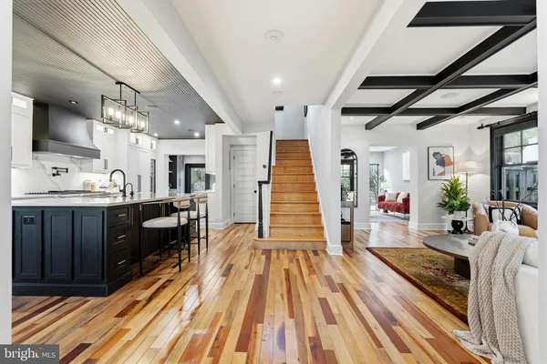 a living room with stainless steel appliances kitchen island granite countertop furniture wooden floor and a sink