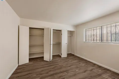 an empty room with wooden floor closet and windows