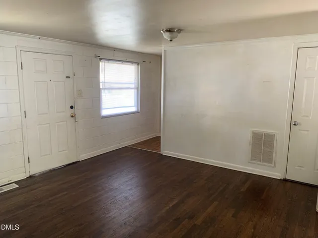 an empty room with wooden floor and window