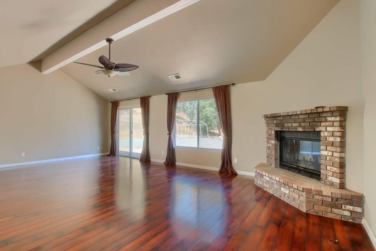 46911 Veater Ranch Road Coarsegold, CA 93614 - Photo 8 of 41 a view of an empty room with wooden floor fireplace and a window