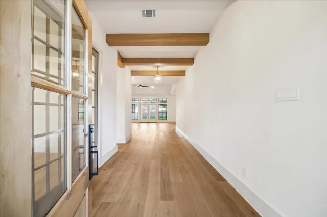 a view of a hallway with wooden floor and a bathroom