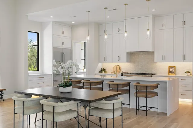 a kitchen with stainless steel appliances granite countertop a table chairs stove and white cabinets